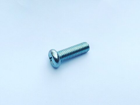 Close-up of silver metal Phillips head screws arranged on a clean white background, showing threaded fasteners used for construction, assembly, and DIY projects.
