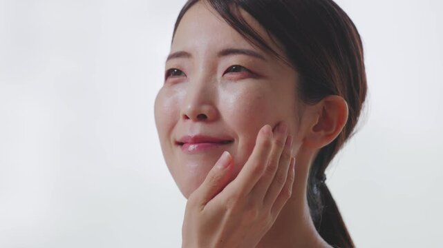 指先で頬の感触を確かめる女性の美肌イメージ
