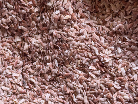 Full frame background of flattened red rice flakes (also known as red poha or aval) piled together