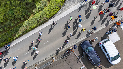Naklejka premium Aerial drone view of people running half marathon race in city, shadows of runners on road racing sport competition, top-down view of athletes and spectators, Venlo, the Netherlands
