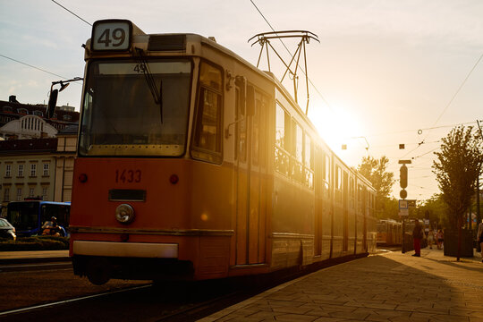 Yellow tram at city stop at sunset