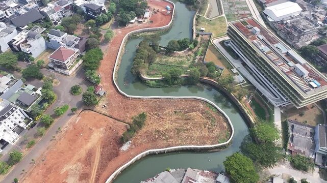Aerial view of urban development with curved river, construction site, and residential housing Drone perspective of a developing cityscape featuring a winding river, earthworks, and scattered building