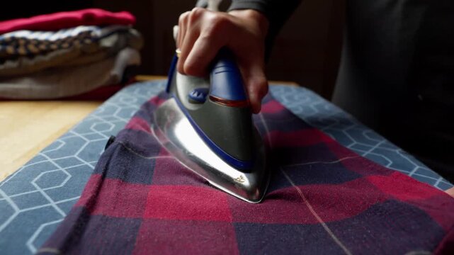 Ironing a plaid shirt to remove wrinkle, with steam rising