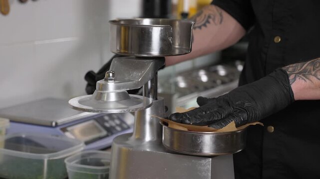 The process of cooking meat patties for a burger. A professional chef, wearing disposable gloves, prepares raw burger patties using a special burger press. The cooking of burgers in a restaurant. 