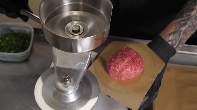 The process of cooking meat patties for a burger. A professional chef, wearing disposable gloves, prepares raw burger patties using a special burger press. The cooking of burgers in a restaurant. 