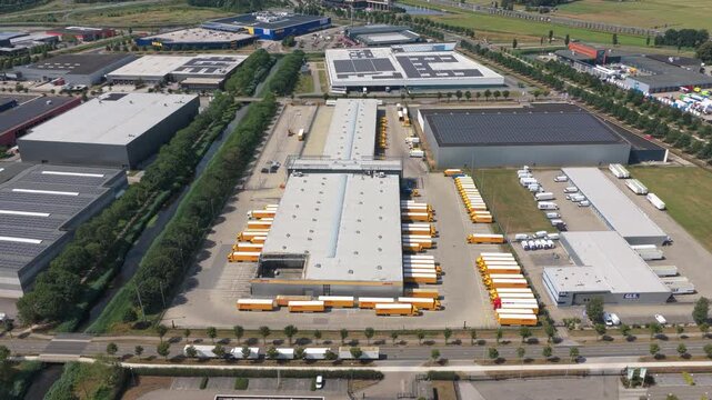 Aerial perspective of a large distribution hub with yellow delivery vans and trucks parked at the loading docks, ready for shipment