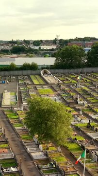 60FPS reversing vertical social ratio aerial video of Milltown Cemetary and the Republican Plot in West Belfast, Northern Ireland in the UK on a bright sunny day. Produced with Rec709 colour.