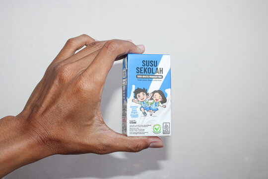 Person Holding Small School Milk Carton Box. August 5, 2026, in Sukoharjo, Indonesia