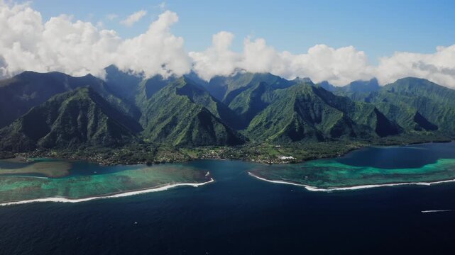 Aerial drone shot over the reef lined coastline near Teahupoo, Tahiti, clear blue sky and bright sunlight defining the turquoise water below.