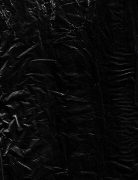 Dark, abstract crumpled plastic texture. Its intricate wrinkles and folds form a dramatic, moody background with deep shadows and subtle highlights, perfect for grunge or distressed designs