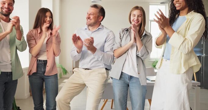 Team coworkers give applause and clapping for success. Happy diverse group in a bright office during celebration. A confident leader joins people applause proudly. We cheer as one team.