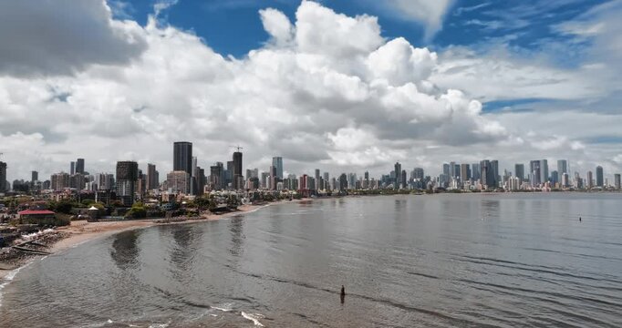 Beautiful aerial view of Mumbai city skyline along the Arabian Sea, featuring modern high-rise buildings, sandy beaches, and a vibrant coastal landscape under a bright blue sky.