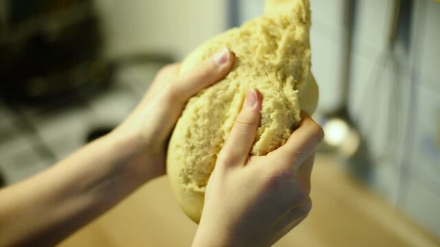 Close up of hands kneading raw pastry dough showing rich texture