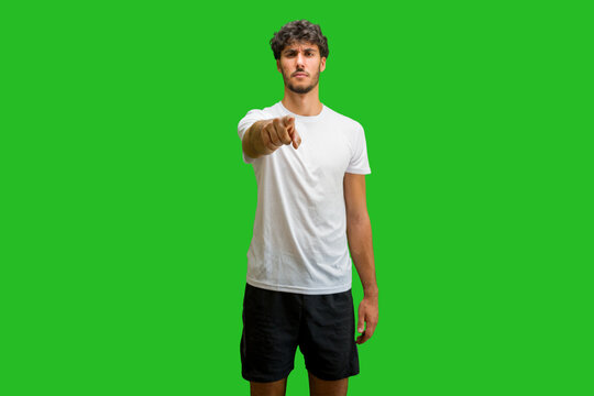 Young man wearing t-shirt standing over isolated chroma background pointing displeased and frustrated to the camera, angry and furious with you
