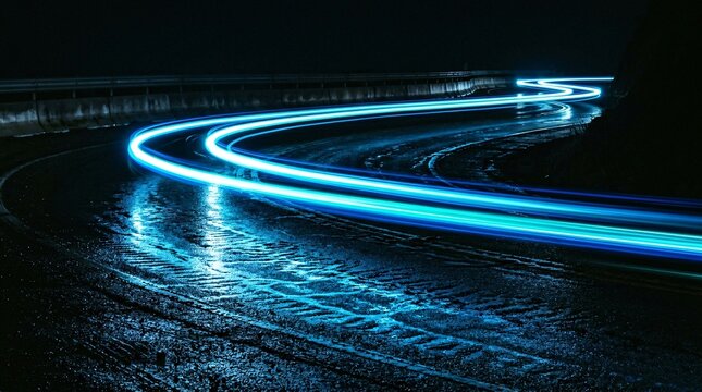 Long exposure blue light trails curving along a wet asphalt road at night creating a dynamic sense of extreme speed.