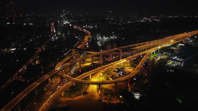 A stunning aerial night view of Atal Setu (Mumbai Trans Harbour Link), showcasing the intricate network of illuminated flyovers and highways glowing in golden light.