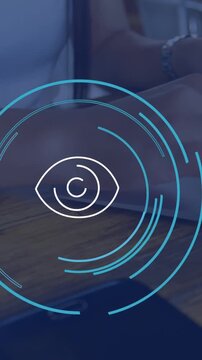 Animation of eye icon over caucasian businesswoman using laptop in office