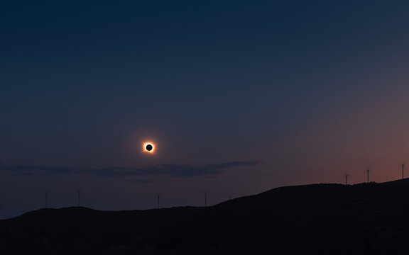 Wide angle of total solar eclipse over the hills of Arnedillo in northern Spain with wind turbines in August 2026