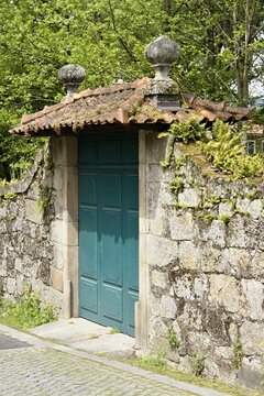 Old stone wall with green door and tiled roof. Portugal - Norte