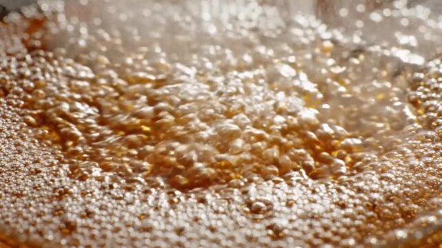 Macro shot of carbonated fizzy liquid pouring into glass with rising bubbles and foam