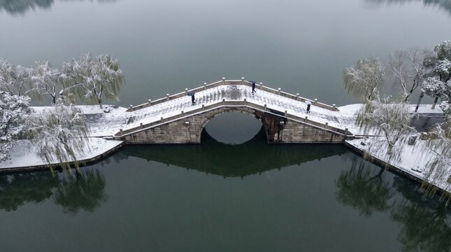 Arched stone bridge spanning frozen waterway in winter landscape