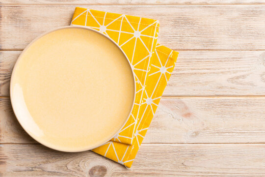 Top view on colored background empty round yellow plate on tablecloth for food. Empty dish on napkin with space for your design