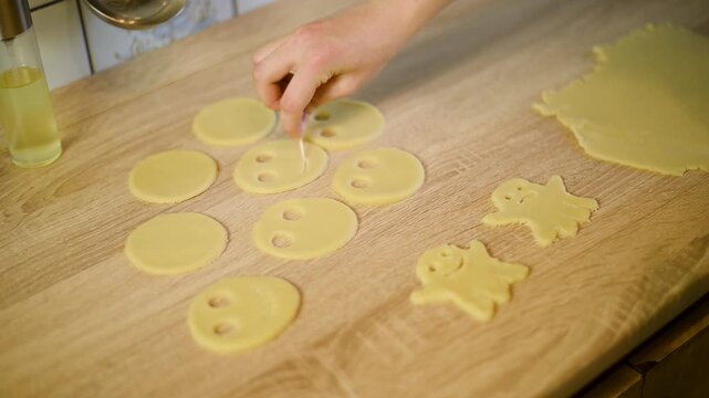 Shaping funny faces on round raw cookie dough blanks with tools