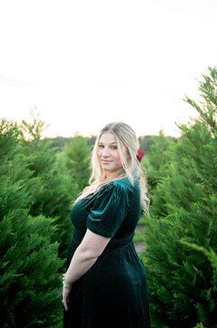 Blonde woman in green velvet dress at a tree farm
