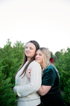 Two women share a tender hug at a tree farm