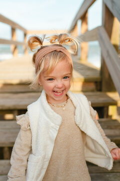 Happy little girl with pigtails on beach steps by ocean