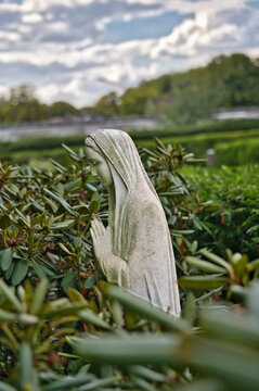 Betende Marienfigur inmitten  von gr&uuml;nem Rhododendron auf dem Hauptfriedhof M&uuml;lheim Ruhr