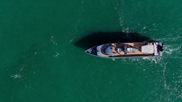 Luxury yacht sails through sparkling sea after leaving marina. Boat follows calm water. Motorboat completes scenic route. Summer vacation becomes unforgettable