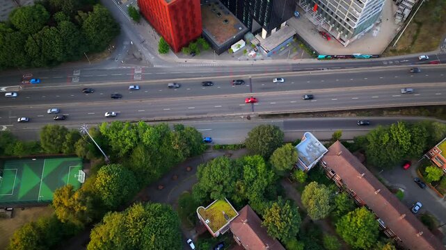 Aerial video looking directly down onto Mancunian Way traffic and adjacent residential housing and developments during golden hour in Manchester.