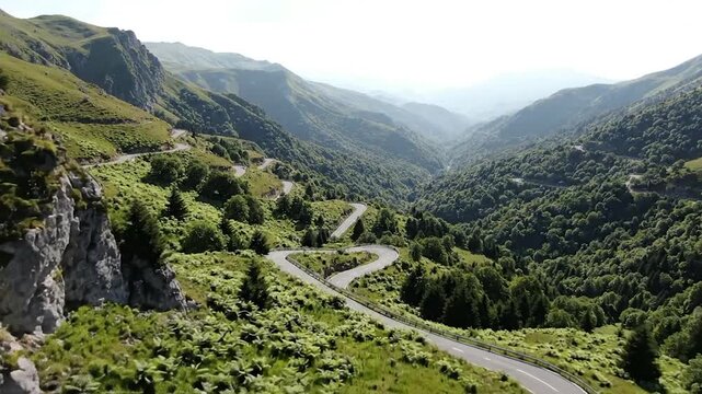 Winding mountain road aerial shot with lush green slopes and deep valley views in cinematic motion.
