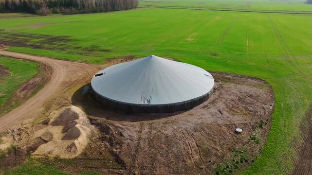 Drone orbits covered farm reservoir surrounded by vivid green spring croplands