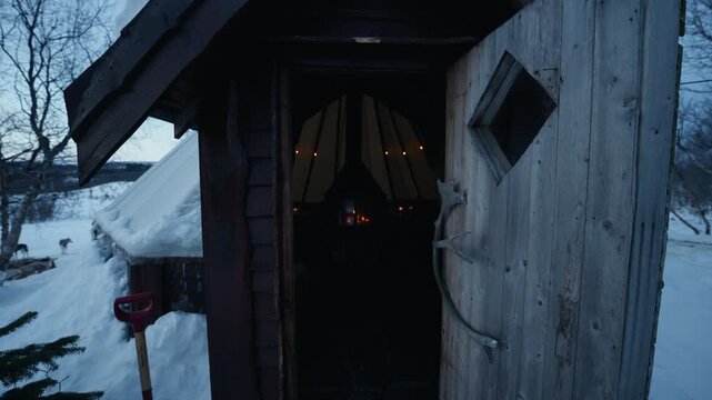 Entrance to traditional Sami lavvu with warm fireplace in snowy Arctic Norway