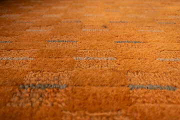 Fototapeta premium Close-up view of an orange textured carpet with subtle gray stripes and plush fibers, ideal as an interior design background conveying warmth, comfort and a cozy modern home atmosphere.