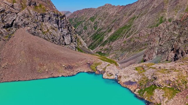 Drone flying backwards from Ala-Kul lake waterfall in Kyrgyzstan