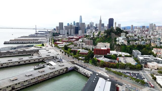 Aerial drone view of San Francisco, California, showing the downtown skyline, Embarcadero waterfront, Bay Bridge, city streets and San Francisco Bay. Wide cinematic establishing footage of the urban