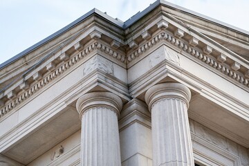 Fototapeta premium Detailed Close-up of Classical Architectural Columns and Cornice Against a Bright Sky