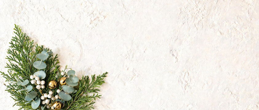 Christmas flat lay background, Minimal winter greenery banner, Holiday pine eucalyptus border, Golden bells berries frame, Elegant seasonal invitation backdrop, Neutral textured wall copyspace.