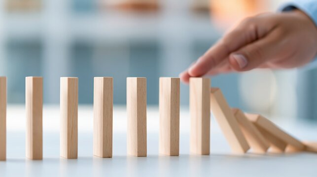 Hand stopping cascading dominoes, symbolizing crisis management, risk prevention, and proactive business strategy