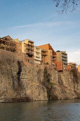 Traditional Houses with Carved Wooden Balconies on the Kura River in Old Tbilisi . Rocky Riverbank of the Mtkvari River © murziknata