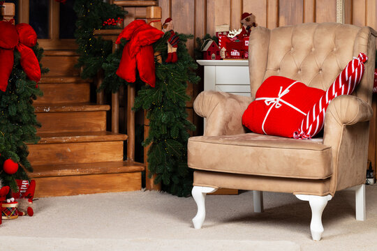 A warm and inviting holiday scene featuring a staircase adorned with festive greenery and red bows, alongside a comfortable armchair holding Christmas presents