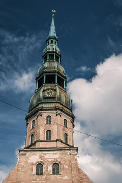 Vertical view of the towering wooden steeple and clock tower of St Peter Church under deep sky in Riga Old Town, Latvia