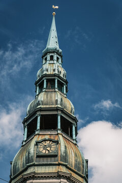 Vertical close-up shot of the ornate copper spire and gold weathercock rooster on St Peter Church tower in Riga Old Town, Latvia
