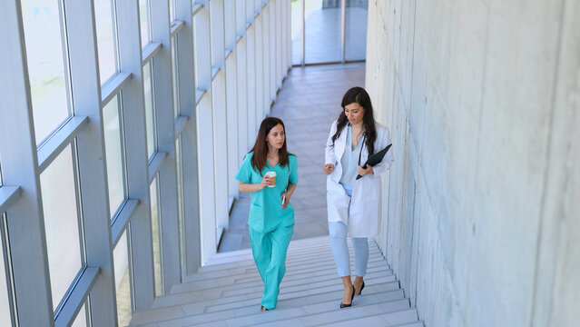Medical professionals walking down hospital staircase discussing work