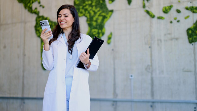 Female doctor using smartphone with global health map