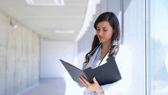 Female doctor reviewing patient folder in hospital corridor