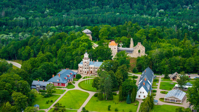 Sigulda Medieval Castle ruins alongside Sigulda New Castle Manor set in dense green woodland, Gauja National Park, Latvia.